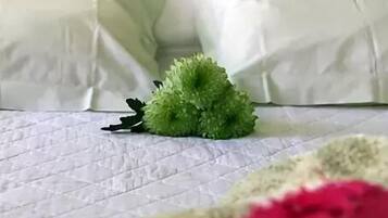 A bed with a green headboard, white bedding, and a green decorative item on the bed.