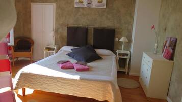 Une chambre à coucher avec un lit, une chaise, une commode et un tableau accroché au mur.