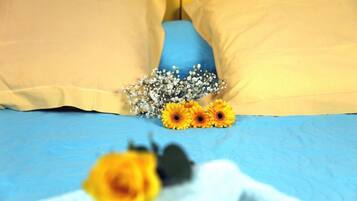 Een bed met blauwe lakens en beige kussens, versierd met gele bloemen en witte gipskruid.