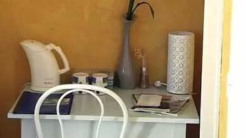 Ein kleiner Essbereich mit Tisch, Stuhl, Blumen in einer Vase, einer Kaffeemaschine und einem dekorativen Gegenstand an der Wand.