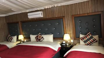 Une chambre d’hôtel avec deux lits, chacun recouvert d’une couvre-lit rouge et blanche, dotée d’une tête de lit sombre à motifs capitonnés et d’un climatiseur mural.