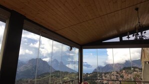 A room with a wooden ceiling and large windows offering a mountain view. - Hotel Aitone (Evisa)