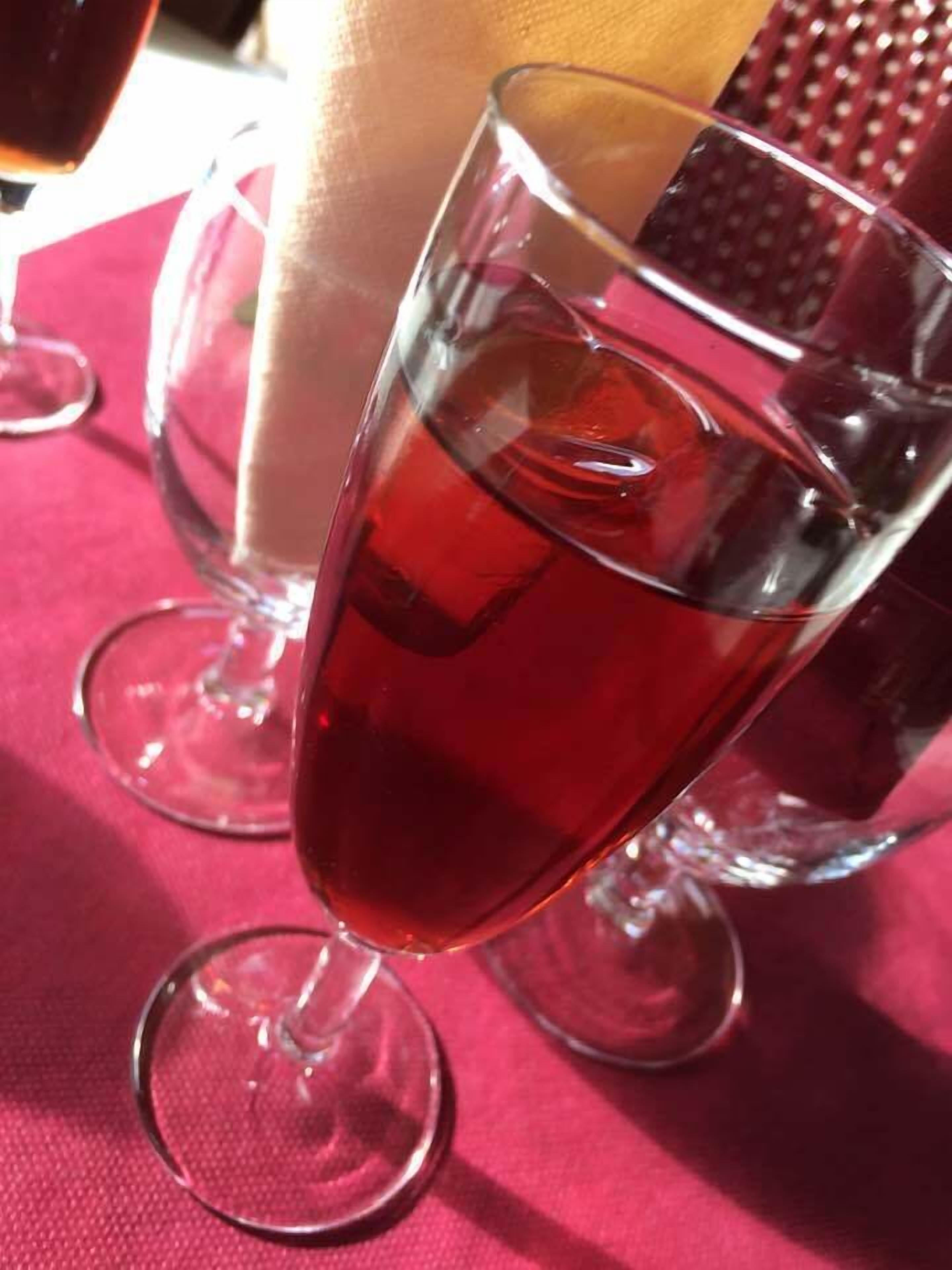 Un got de beguda vermella sobre una taula amb altres gots i una tovallola.