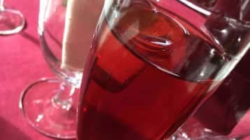 A glass of red beverage on a table with other glasses and a napkin.