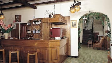 Een gezellige barruimte met houten meubels, een geruite vloer en een rustiek plafond.