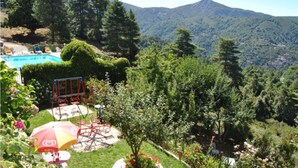 A pool area with lounge chairs, a swing set, and a view of a mountainous landscape. - Hotel Aitone (Evisa)