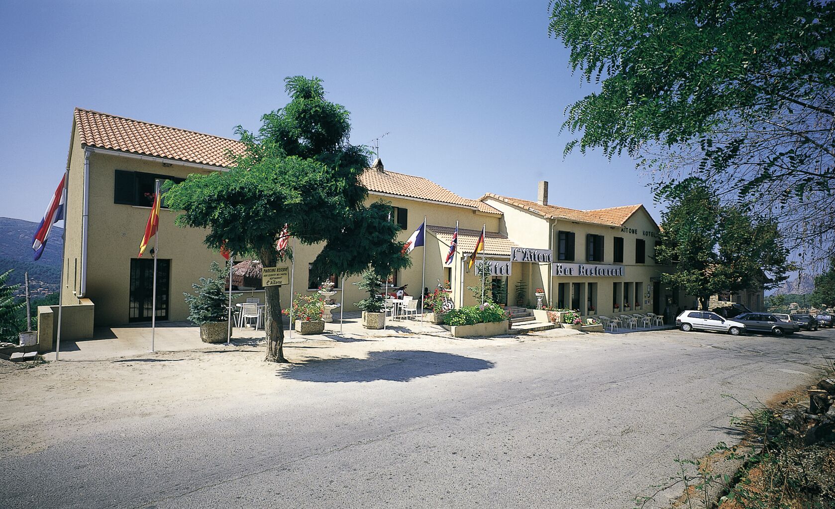 Un hotel con techo de tejas, zona de estar exterior y banderas.