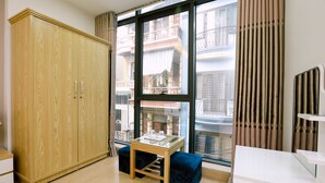 A modern room with a large wardrobe, a small table with a glass top, and a view of the city through large windows. - Tuan Anh Hotel (Hanoi)