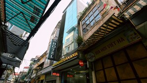 A hotel with a sign reading "HOTEL WHANGHITUANHANG" and a closed storefront with a sign for "BIA HÒI VIỆT HÀ". - Tuan Anh Hotel (Hanoi)