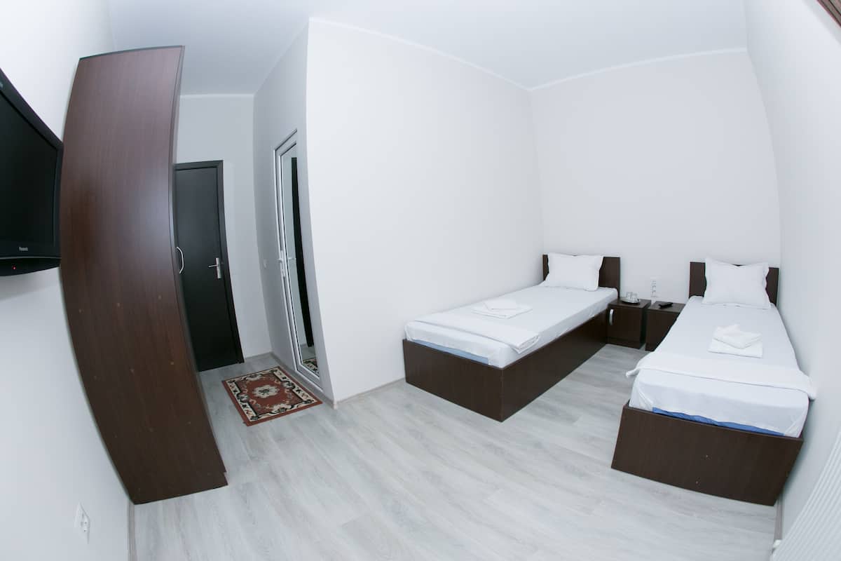 A hotel room with two beds, a wardrobe, a television, and a door.