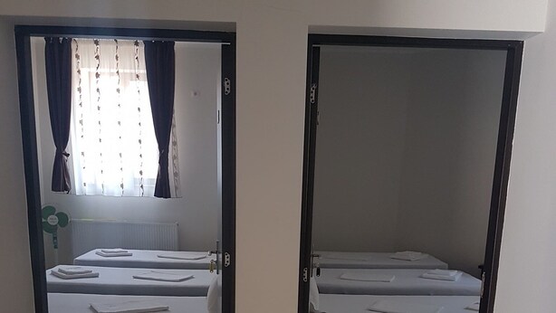 Two single beds with white linens, a radiator, and a window with curtains. - Casa Stefan Galati (Galati)
