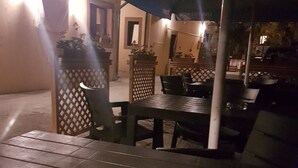 An outdoor patio area with a table and chairs, potted plants, and a clear glass bowl on the table. - Casa Stefan Galati (Galati)
