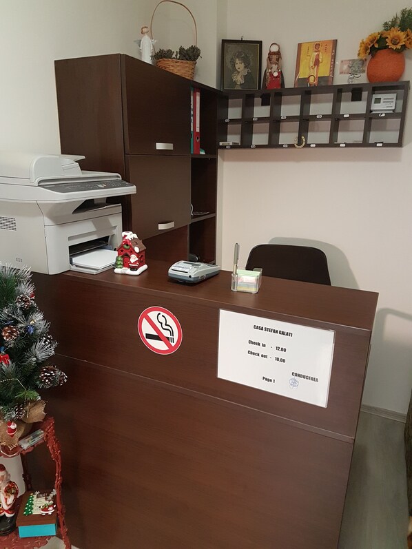 A reception desk with a no-smoking sign, a check-in/out board, and a small Christmas tree decoration. - Casa Stefan Galati (Galati)