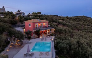Una villa con piscina, area relax esterna e vista sul paesaggio circostante.