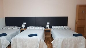 A hotel room with two single beds, each with a pillow and a small bedside table with a lamp. - Noja Rooms (O Pino)