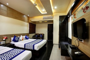Habitación de hotel con dos camas, un televisor y aire acondicionado.