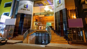 Un hotel con una fachada moderna, una entrada destacada y una escalera que lleva al vestíbulo.