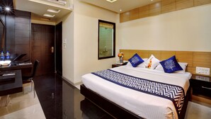 Una habitación de hotel moderna con una cama grande, un escritorio con una computadora portátil y un armario.