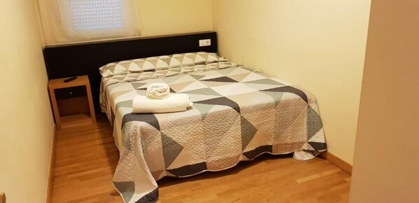 A small, neatly arranged bedroom with a bed, a bedside table, and a window. - Noja Rooms 2 (O Pino)