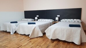 A hotel room with three single beds, each with a white textured bedspread and a dark blue towel. - Noja Rooms 2 (O Pino)