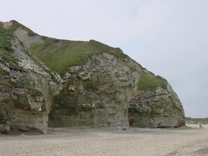 Une falaise rocheuse avec une petite plage à sa base.