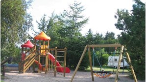 A playground with a slide, climbing structures, and a swing set. - Bygholm Camping Thy (Vesløs)