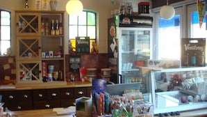 A bar with a counter, shelves with bottles, and a display case with snacks. - Bygholm Camping Thy (Vesløs)