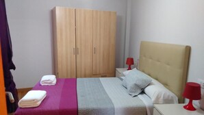 Un dormitorio con cama, armario, mesita de noche y lámpara roja.