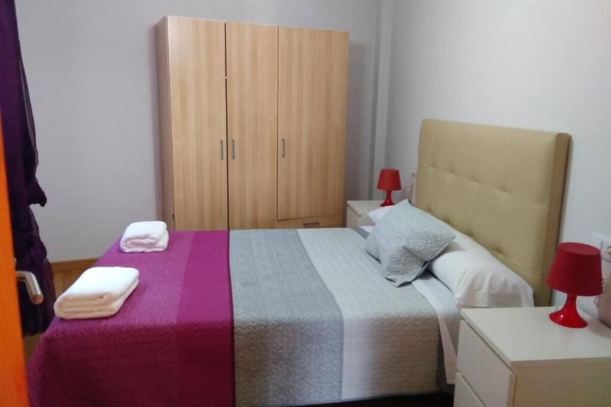 Une chambre à coucher avec un lit, une armoire, une table de chevet et une lampe rouge.