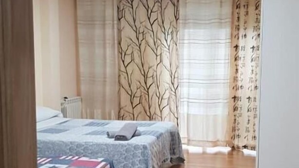 Una habitación con dos camas, un radiador y suelo de madera.