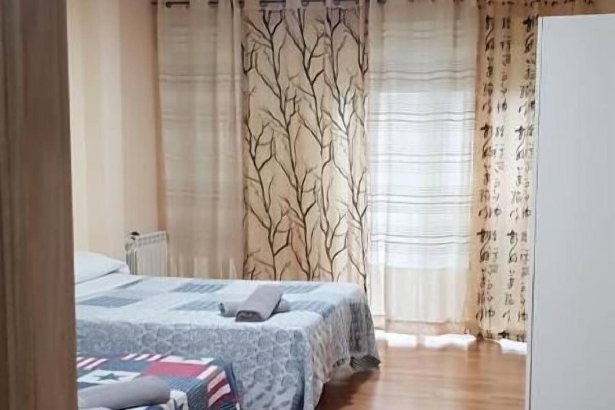 Une chambre avec deux lits, un radiateur et un plancher en bois.