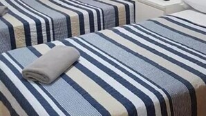 Una habitación de hotel con dos camas, un escritorio, una silla y un cuadro en la pared.