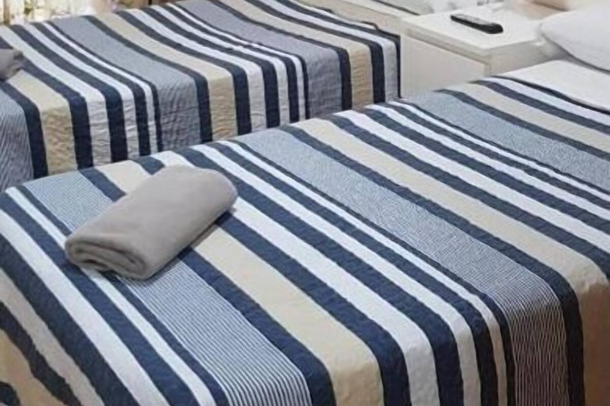 Une chambre d’hôtel avec deux lits, un bureau, une chaise et un tableau au mur.