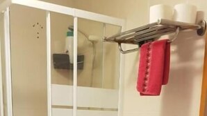 Un baño con inodoro, cabina de ducha, lavabo y toallero.