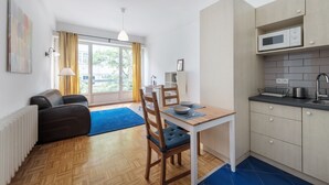 A compact living space with a dining area, kitchenette, and a view of the outdoors. - Friends Avenue Apartment (Warsaw)