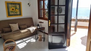 Un salon chaleureux avec un canapé marron, un tableau représentant un tournesol encadré, une petite table sur laquelle est posée une lanterne et un panier en osier.
