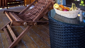 A wooden deck with a wicker table and a wicker chair. - Ocean Tree Beach Resort  & Spa (Port Blair)