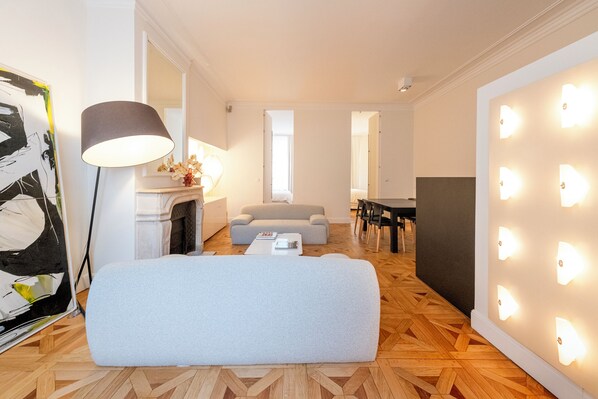 A modern living room with a sofa, a lamp, a fireplace, and a wall with illuminated lights.
