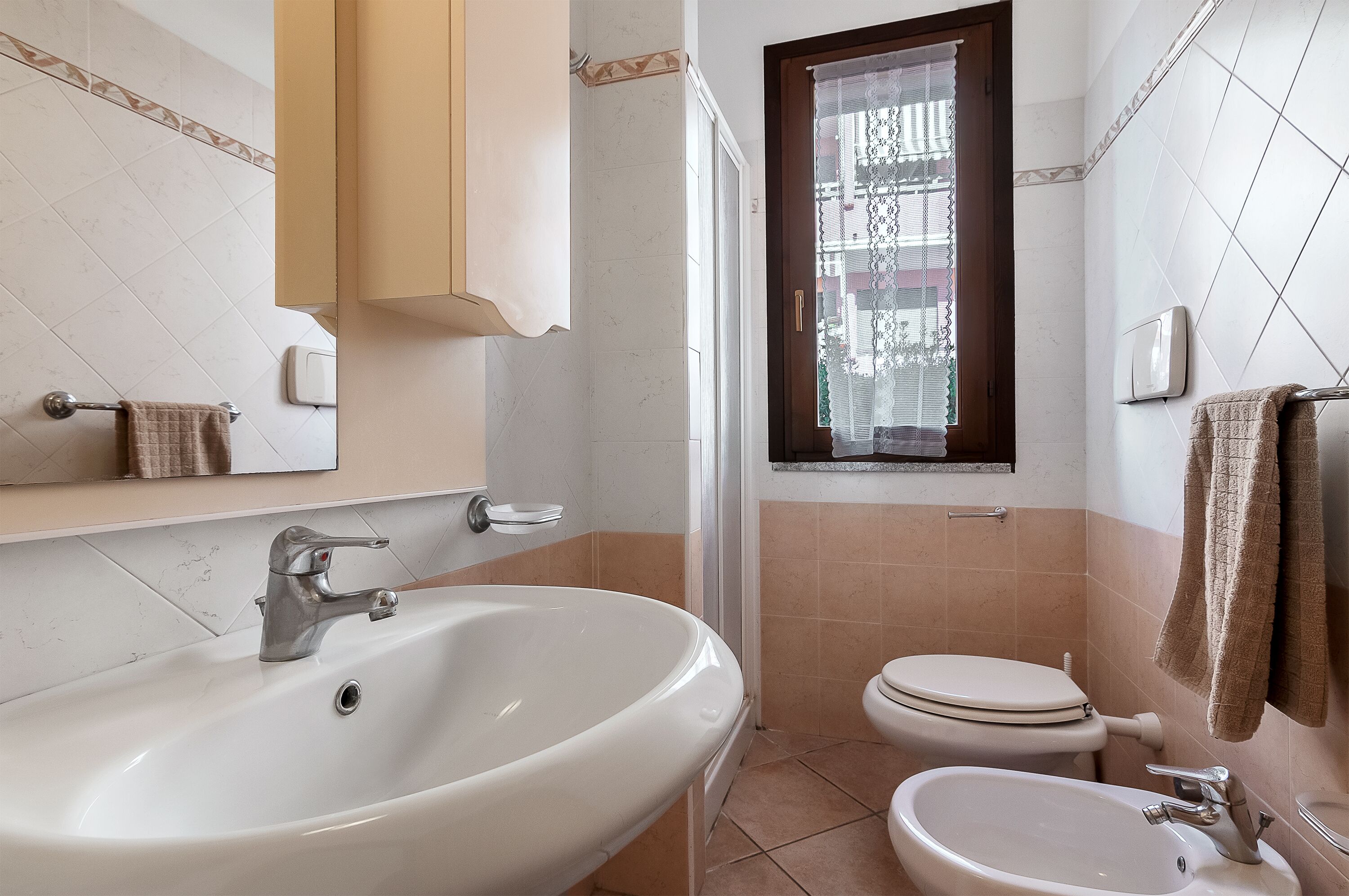 A bathroom with a sink, toilet, and window.
