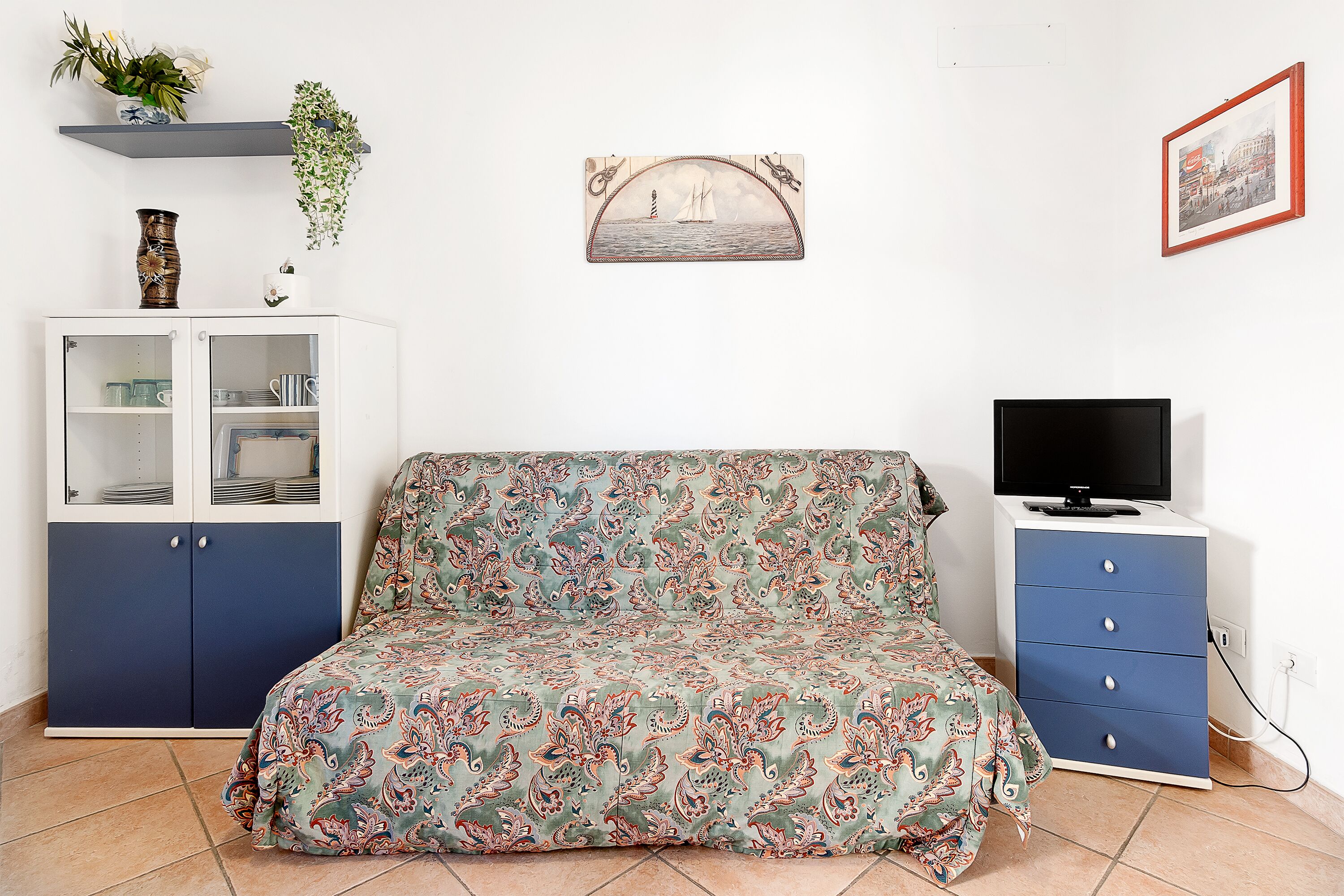 Un dormitorio con cama, armario, televisor y un cuadro en la pared.