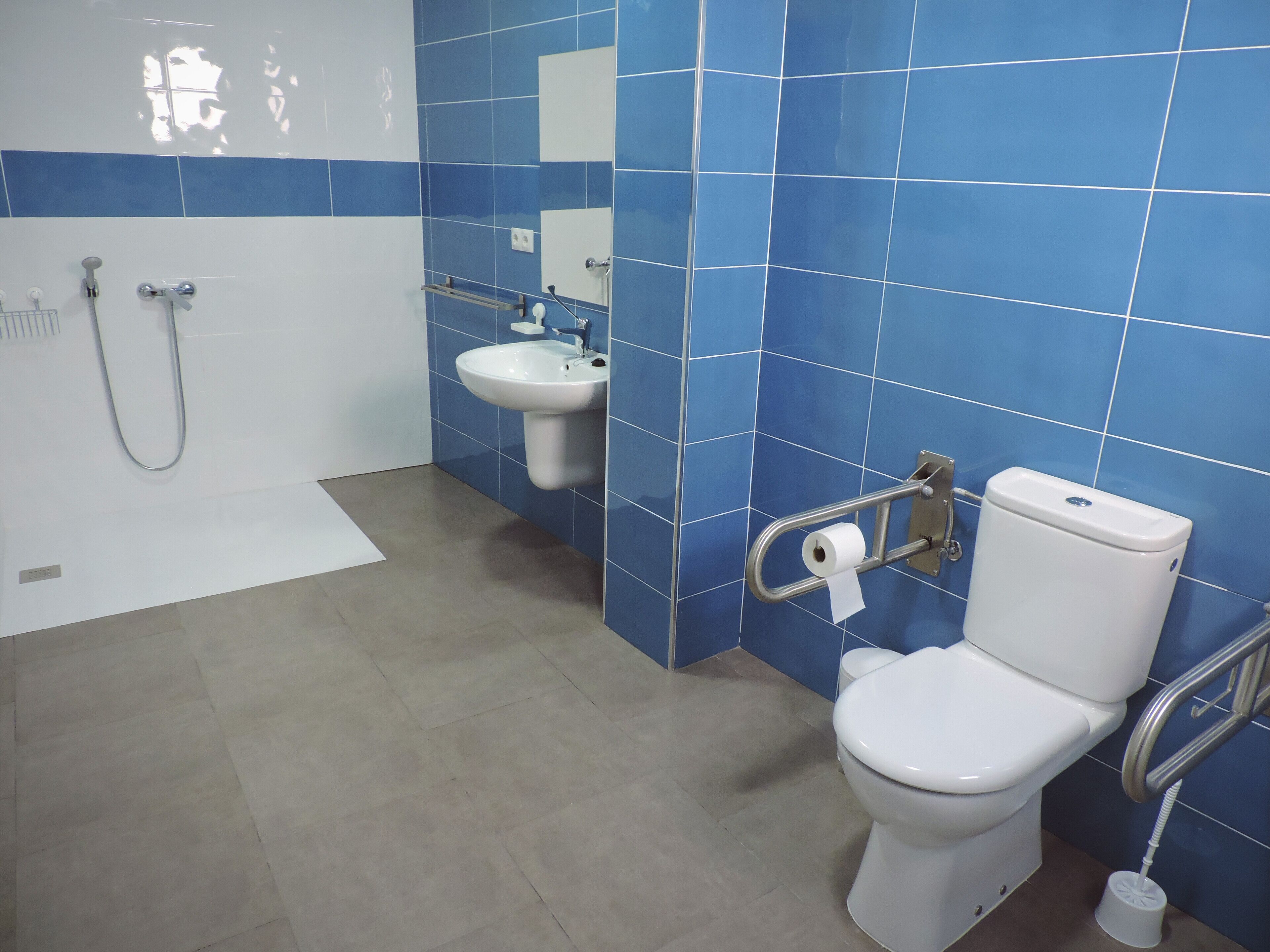 A bathroom with a toilet, bidet, and sink, all equipped with accessibility features.