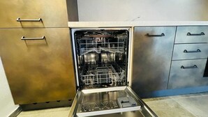 An open dishwasher with racks and a control panel, a stainless steel cabinet with drawers, and a tiled floor. - VILLA LINDA - Studio  sleeps 2-3 (Bardonecchia)