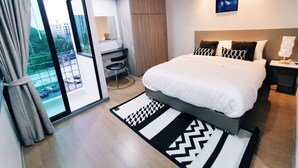 A modern hotel bedroom with a large bed, a desk, and a view of the city through a sliding door. - Star Sukhumvit (Bangkok)