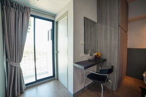 A modern room with a sliding glass door, a small desk with a chair, and a mirror. - Star Sukhumvit (Bangkok)