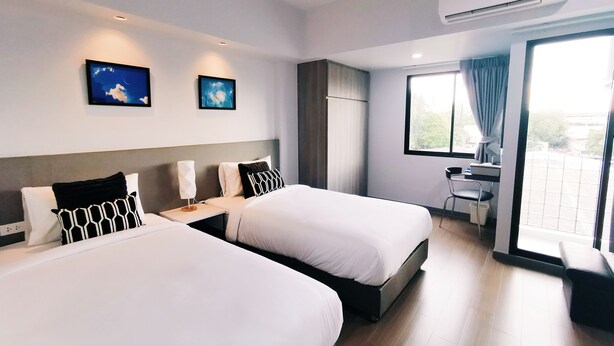 A hotel room with two beds, a desk, a chair, and a large window with curtains. - Star Sukhumvit (Bangkok)