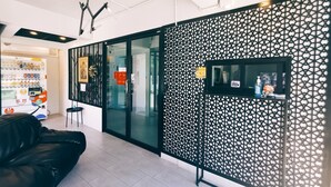 A modern hotel lobby with a black leather sofa, a vending machine, and a decorative wall with a geometric pattern. - Star Sukhumvit (Bangkok)