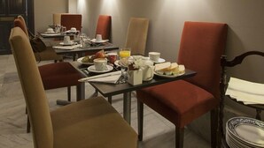 Ein Essbereich mit einem Tisch für vier Personen, gedeckt mit Tellern, Tassen und einer Obstschale.