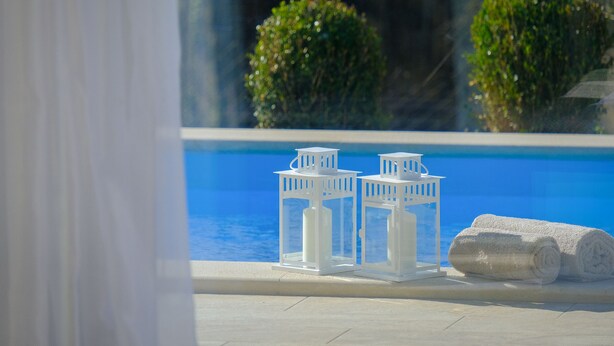 A poolside area with two white lanterns and two rolled towels. - Brand new 2019 villa with pool, barbecue, WiFi, bicycles, dishwasher, washing machine (Tinjan)