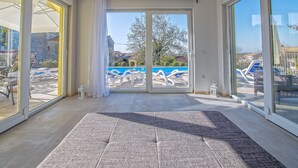A spacious room with large sliding glass doors leading to an outdoor pool area. - Brand new 2019 villa with pool, barbecue, WiFi, bicycles, dishwasher, washing machine (Tinjan)