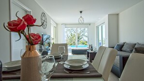 A dining area with a table set for two, a vase with flowers, and a view of the outdoors. - Brand new 2019 villa with pool, barbecue, WiFi, bicycles, dishwasher, washing machine (Tinjan)
